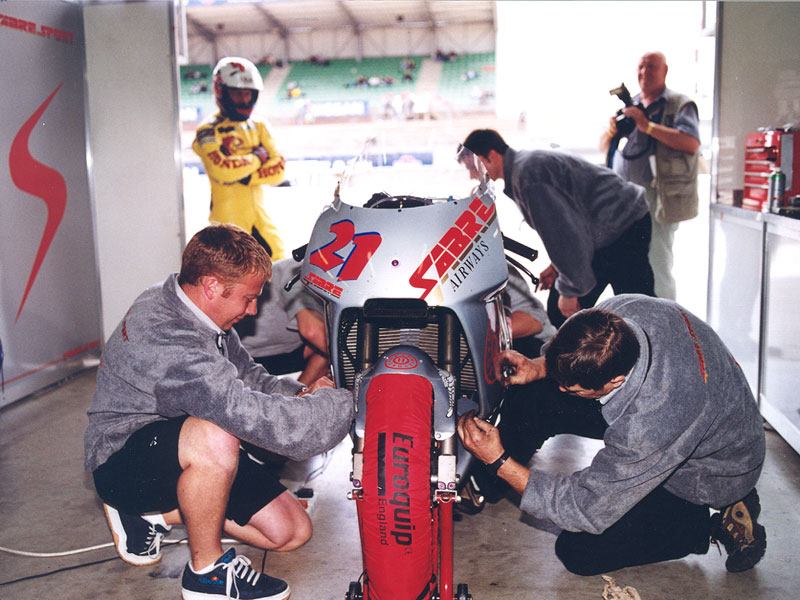 Ron Haslam waits in the background as the fairing is re-fitted to the Honda NSR500V2